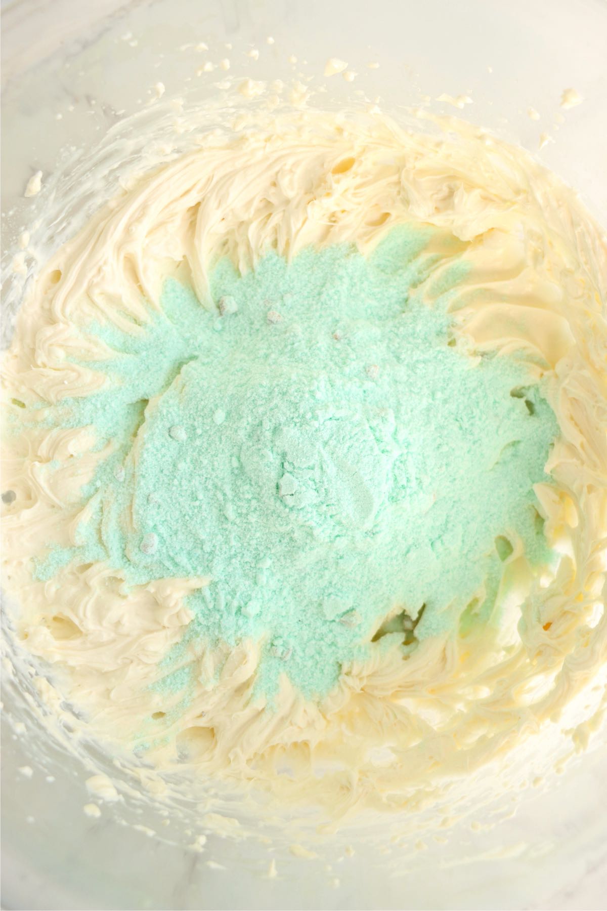 A mixture of whipped cream cheese and pistachio pudding mix in a bowl