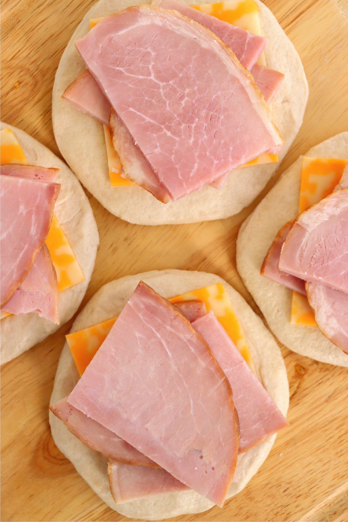 slices of ham on top of cheese and refrigerated biscuits 