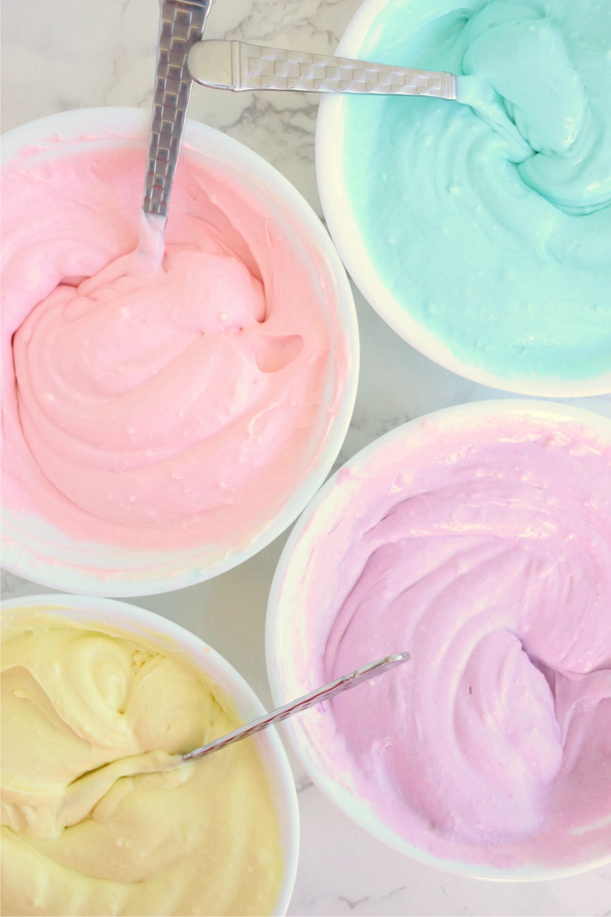 Four bowls of pastel colored cheesecake batter