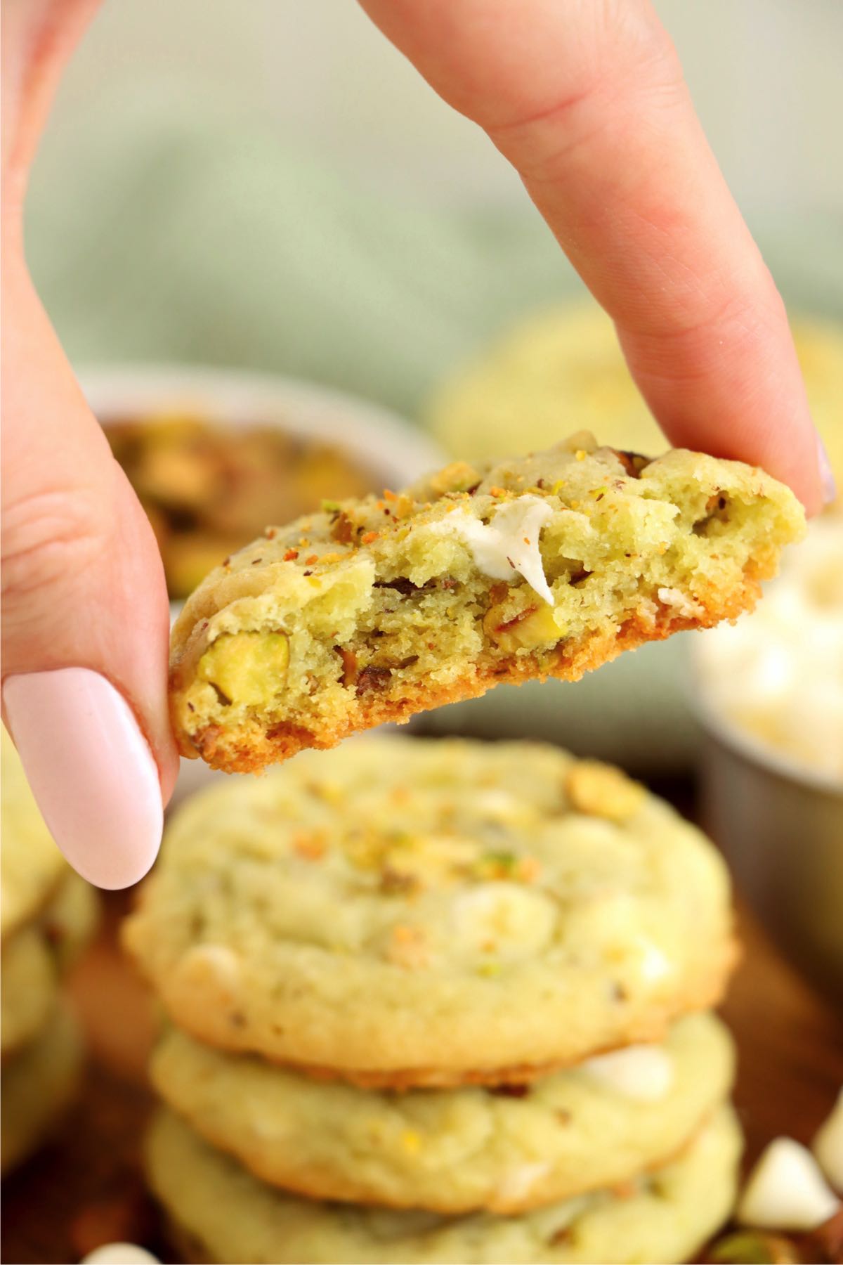 hand holding a half-eaten pistachio pudding cookie