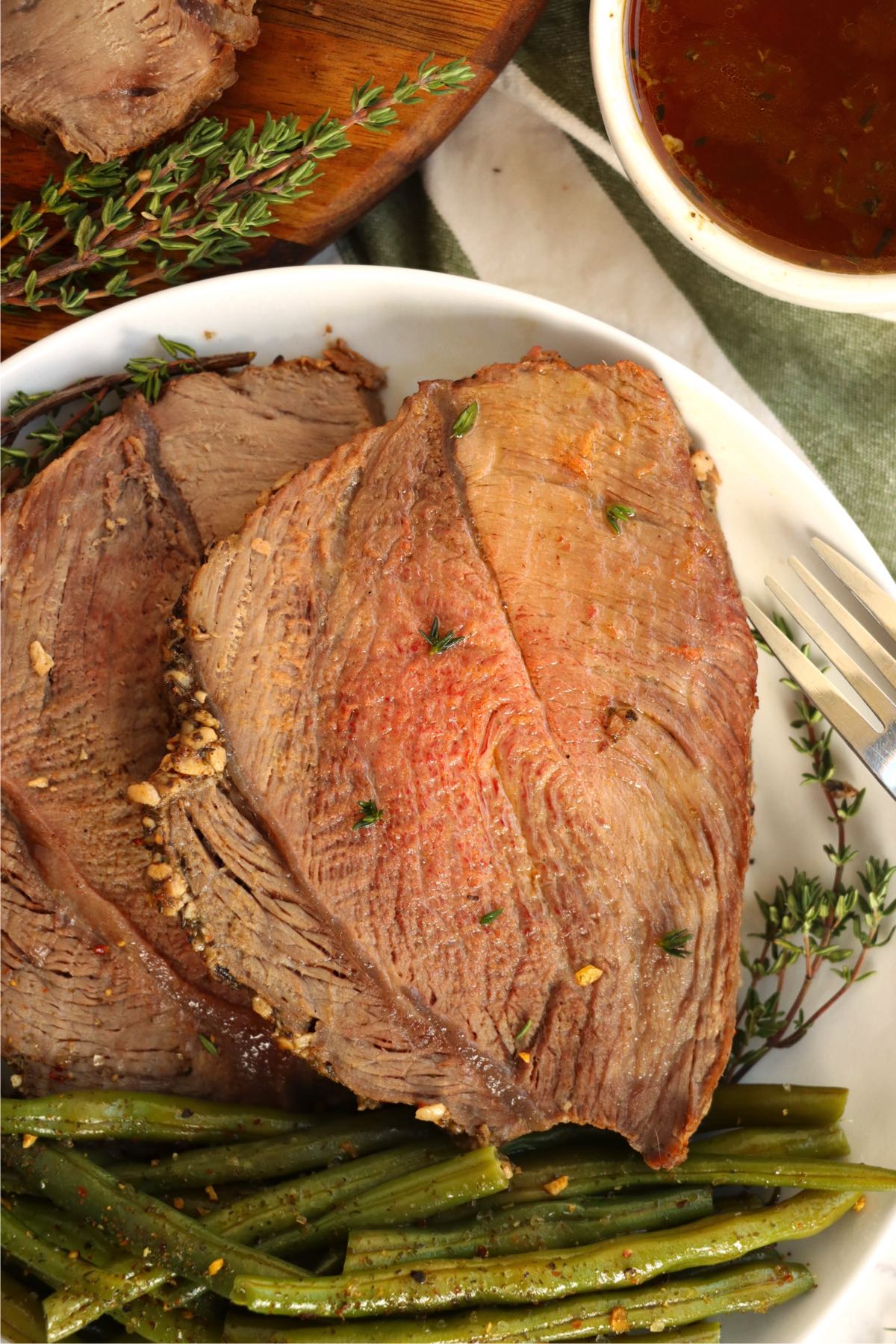 close up of pieces of prime rib garnished with thyme on a white plate