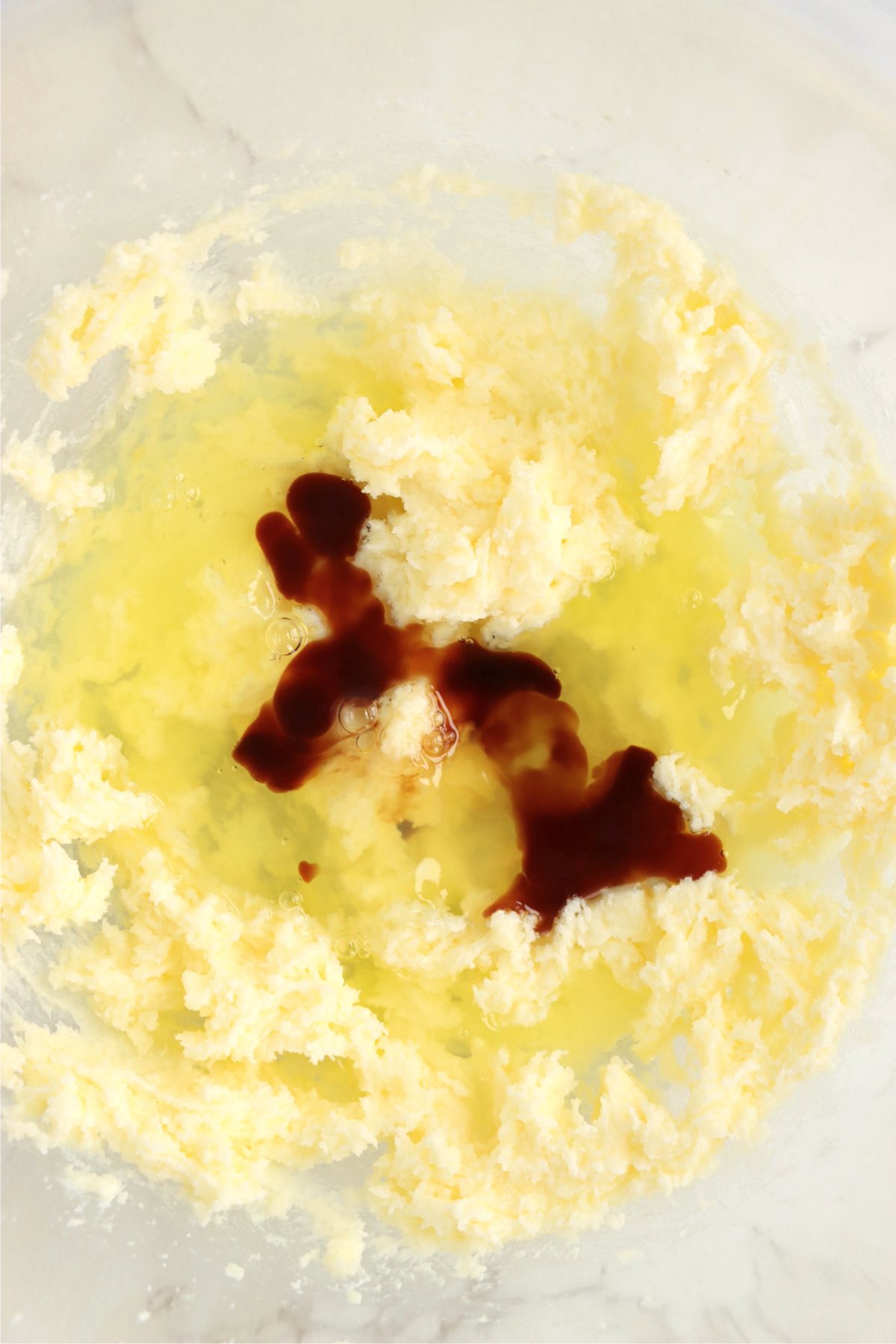 Egg whites and vanilla added to whipped butter in a bowl