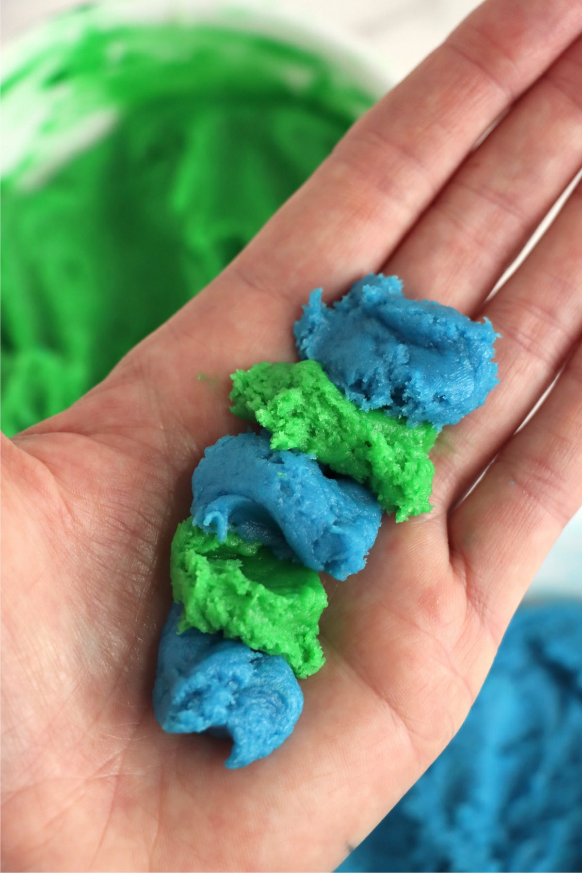 hand holding blue and green cookie dough