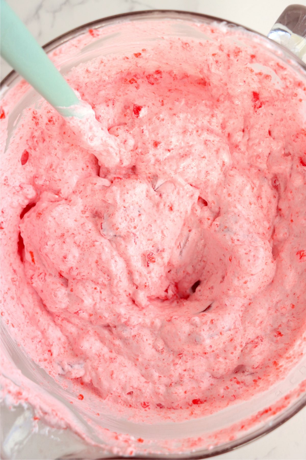 mixing together whipped topping and strawberry gelatin