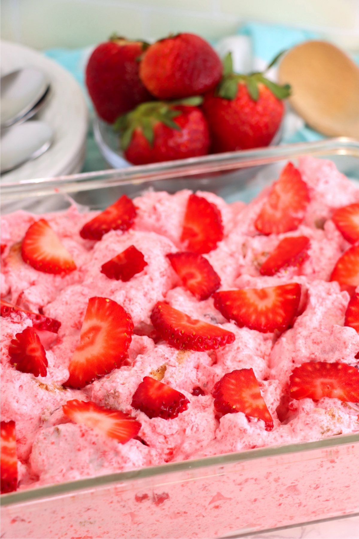 Glass cake pan filled with strawberry gelatin dessert and topped with fresh strawberries