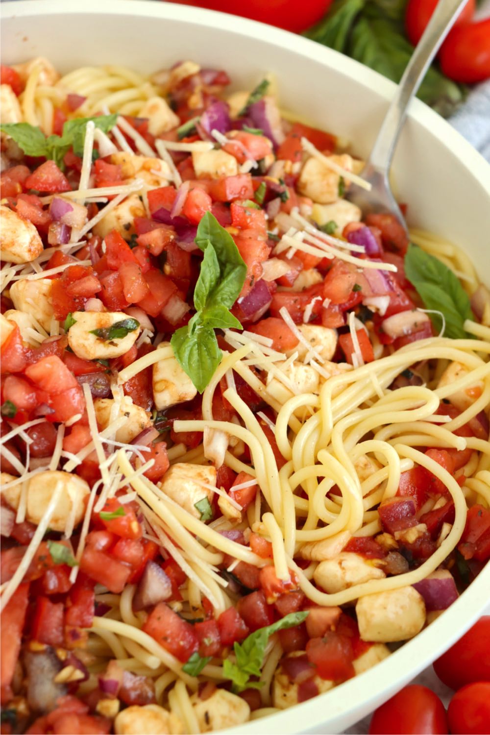 big white bowl filled with bruschetta pasta salad made with long spaghetti.