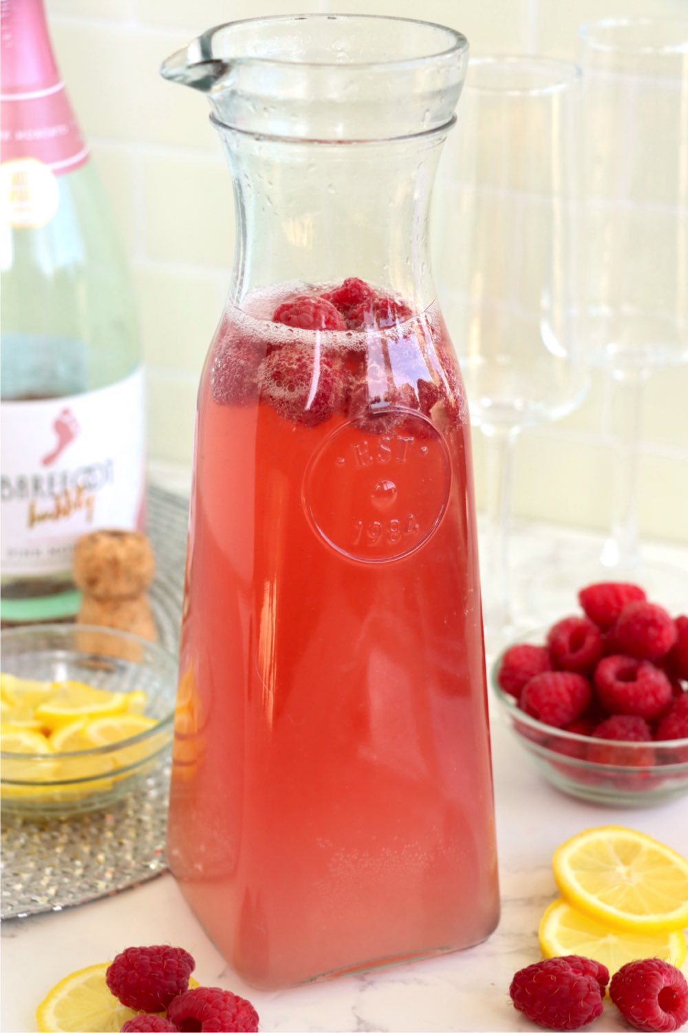 a carafe filled with raspberry mimosa cocktail