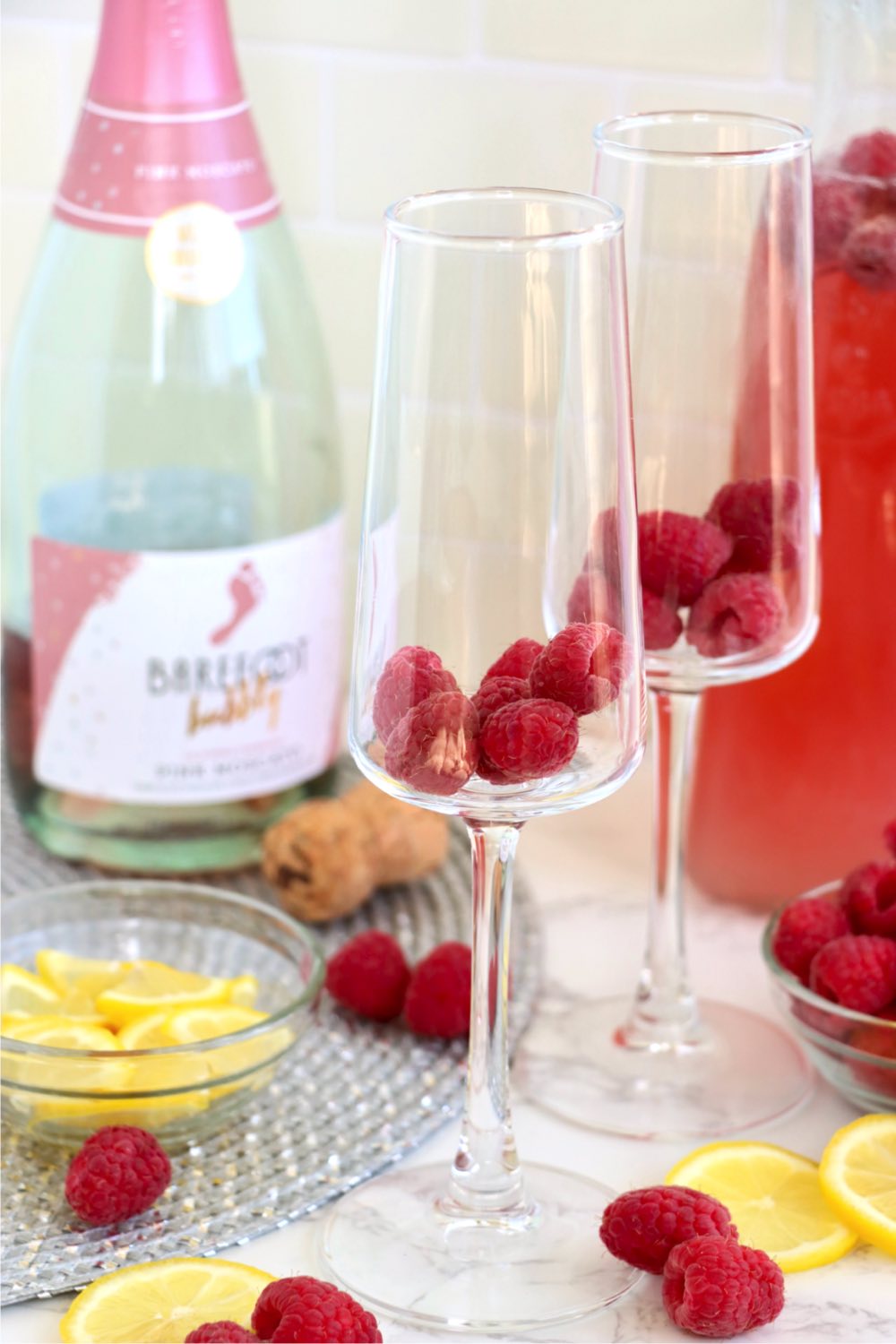 two champagne glasses filled with a handful of raspberries
