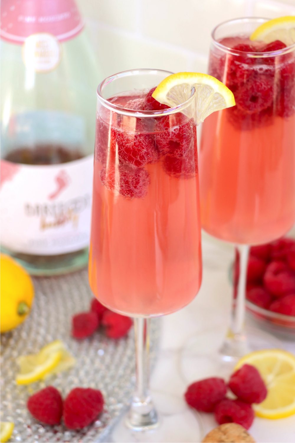 Two champagne flutes filled with raspberry mimosa