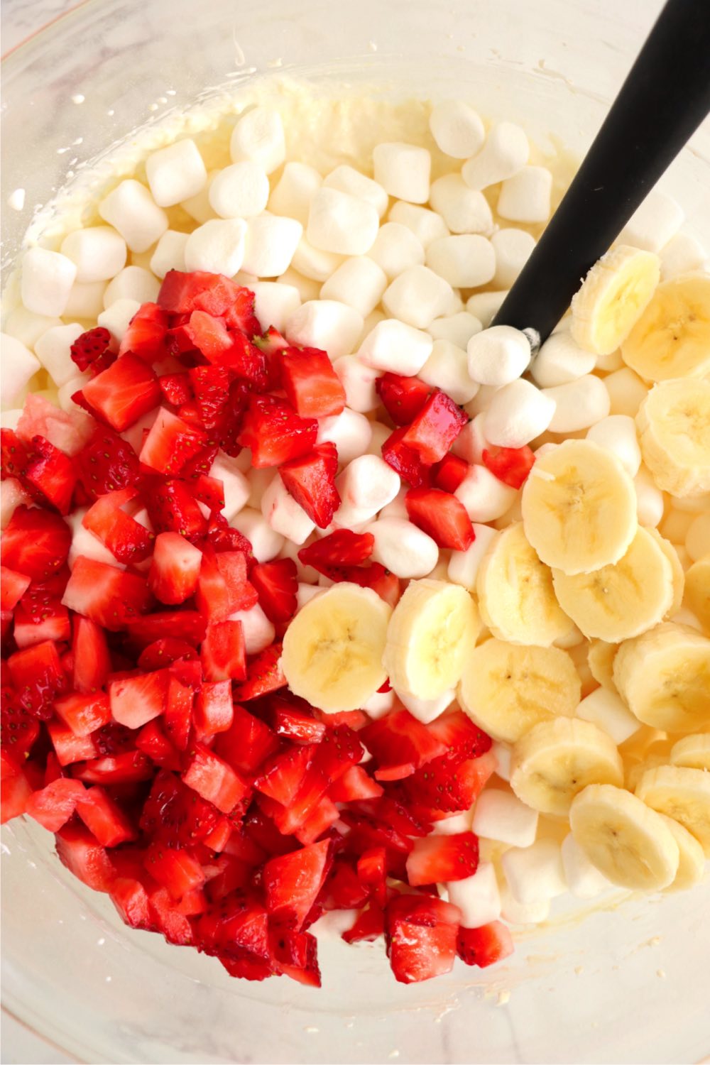 Bowl filled with diced strawberries, sliced bananas and marshmallows.