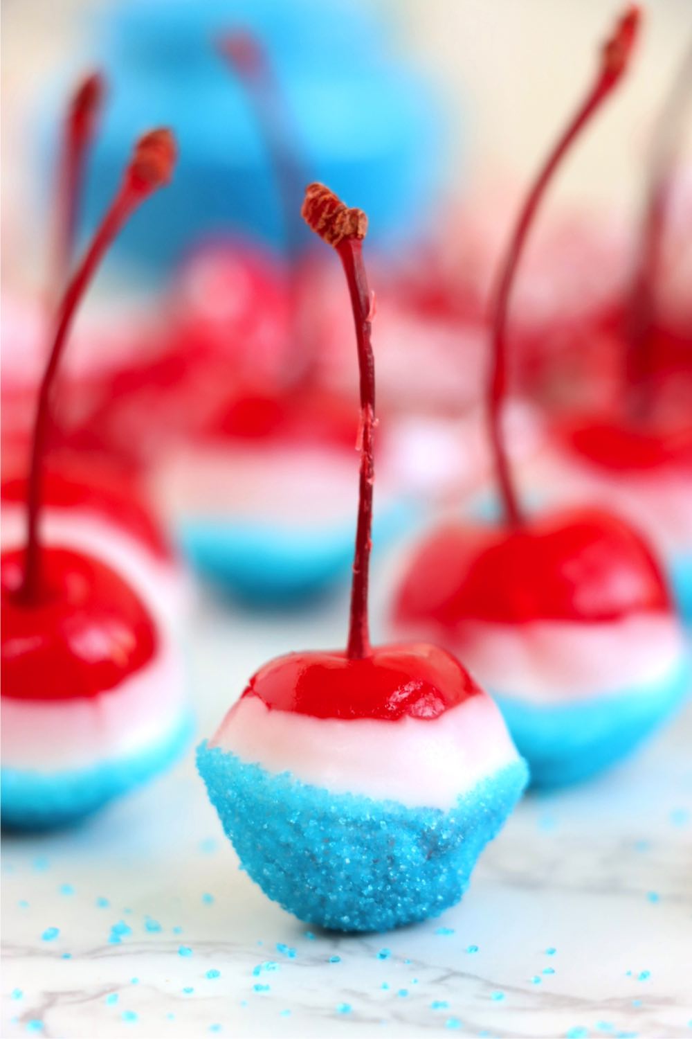 Stemmed cherry dipped into almond bark and blue sprinkles for 4th of July.