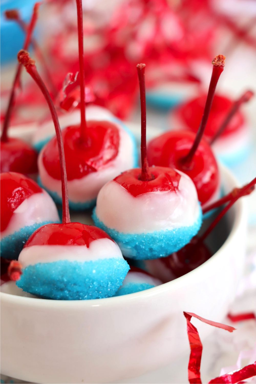 White bowl filled with red, white and blue decorated cherries.