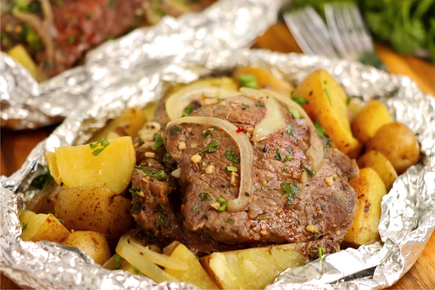 Steak, potatoes and onions in a foil packet.