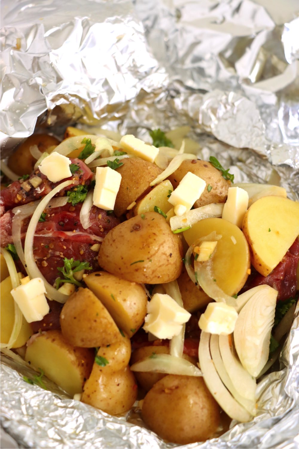 steak, potatoes and butter in foil packets.