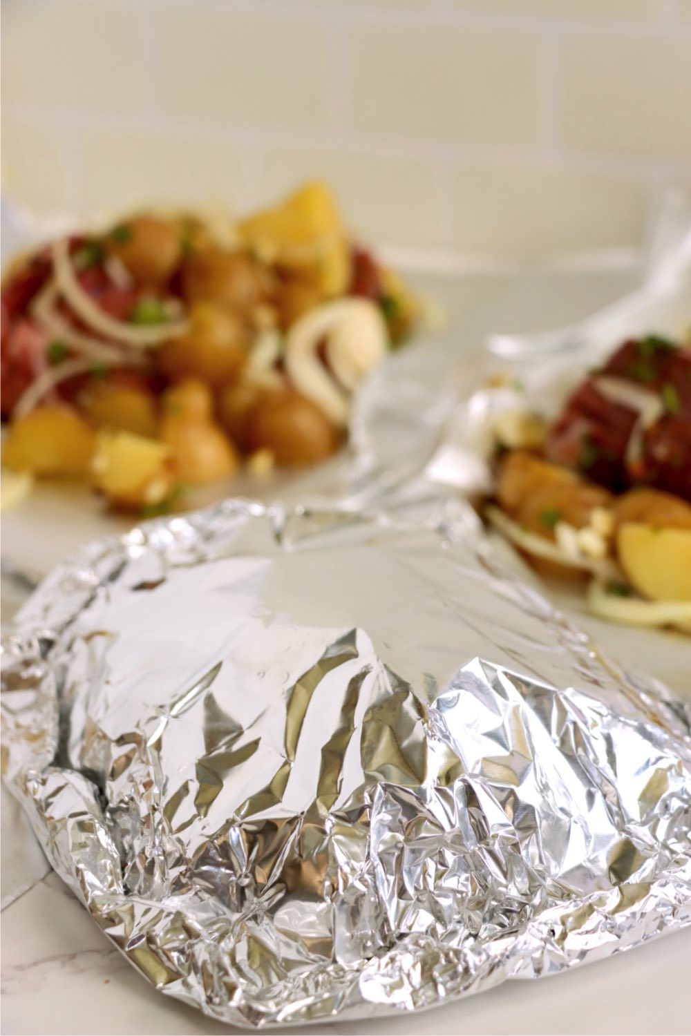 Steak and potatoes enclosed within a foil packet.