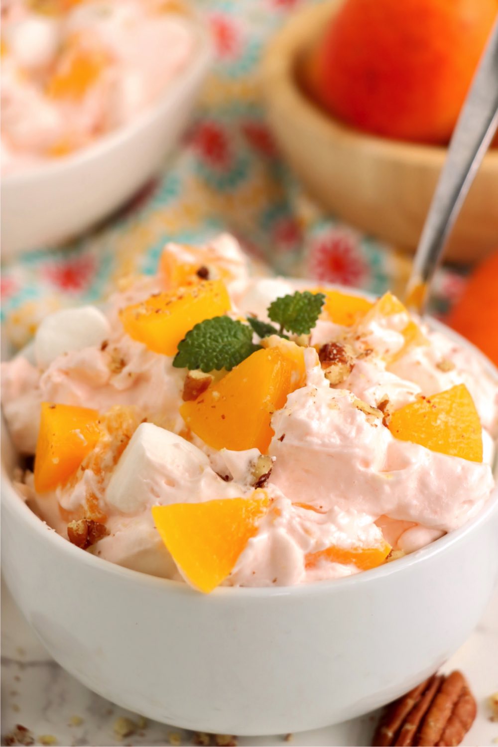 a peach jello fluff salad topped with peaches and a sprig of mint.