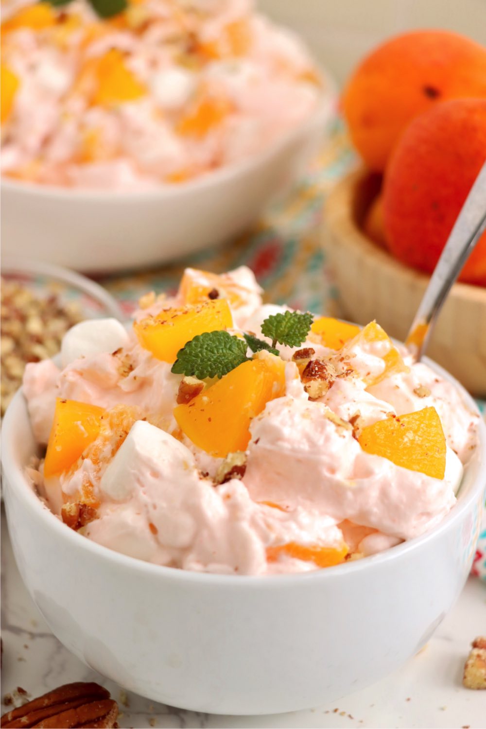 small bowl with a spoon filled with a peach fluff salad.