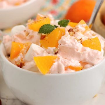 White bowl filled with a peach whipped cream salad.