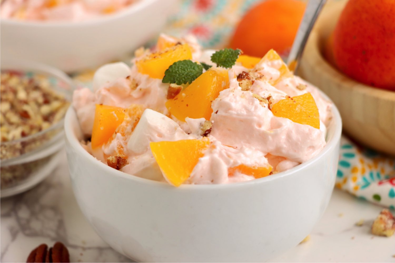 White bowl filled with a peach whipped cream salad.