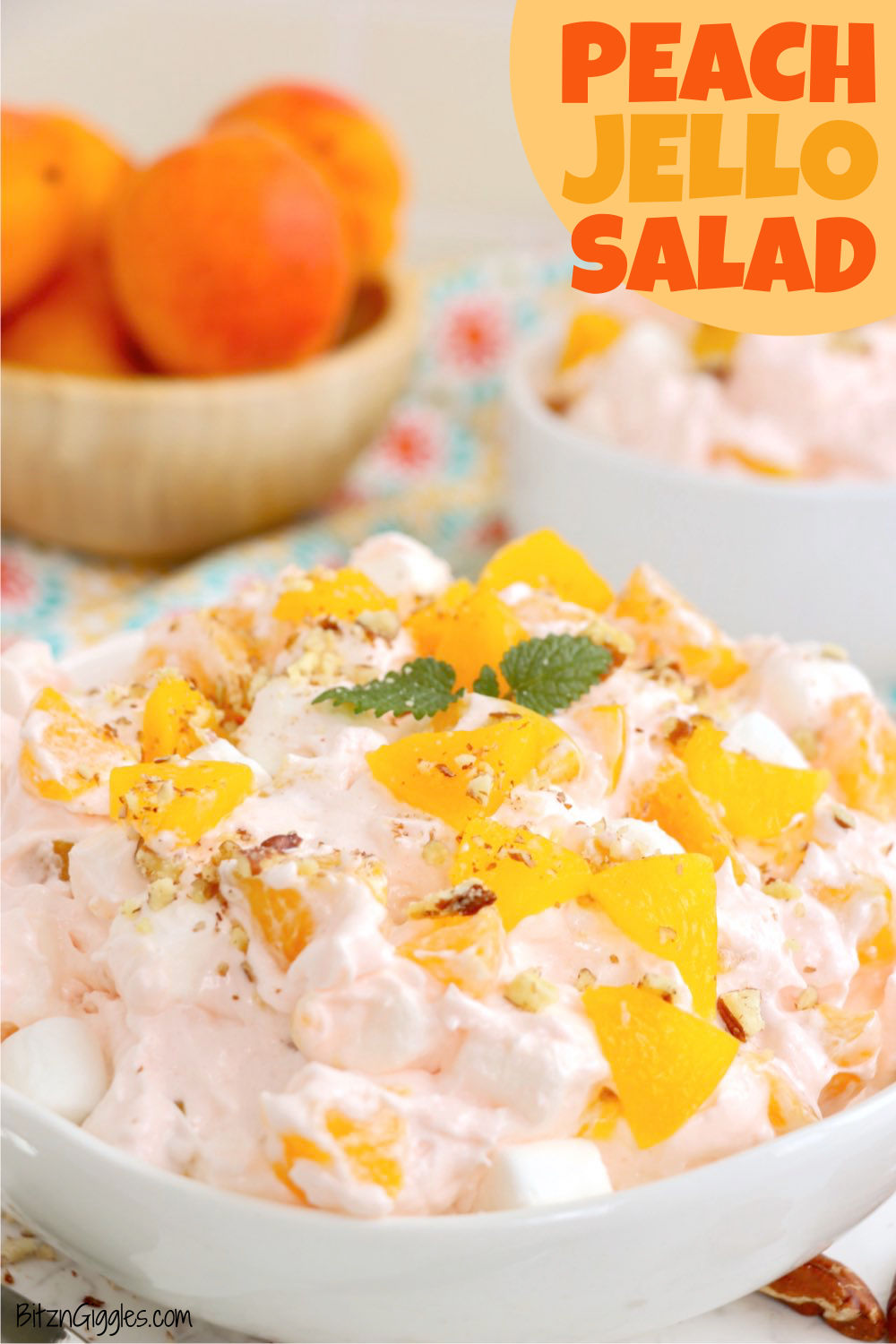 Bowl of peach jello salad topped with canned peaches and a sprig of mint.