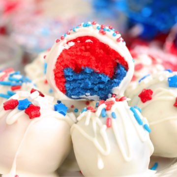 stack of vanilla coated truffles with a half eaten red, white and blue truffle on top.