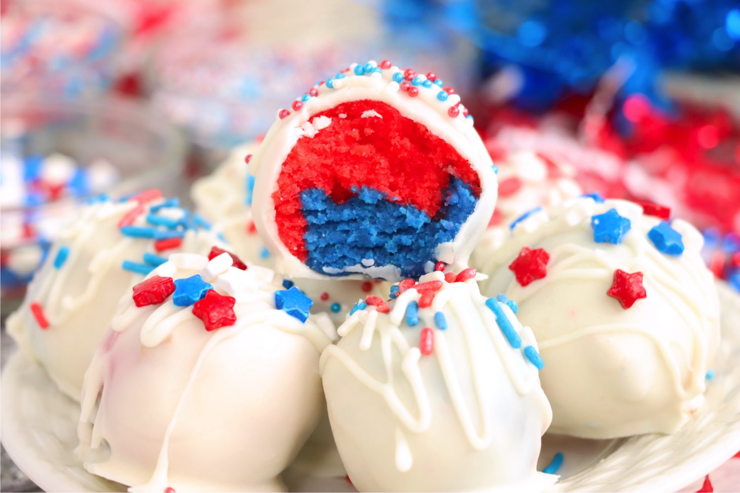 stack of vanilla coated truffles with a half eaten red, white and blue truffle on top.