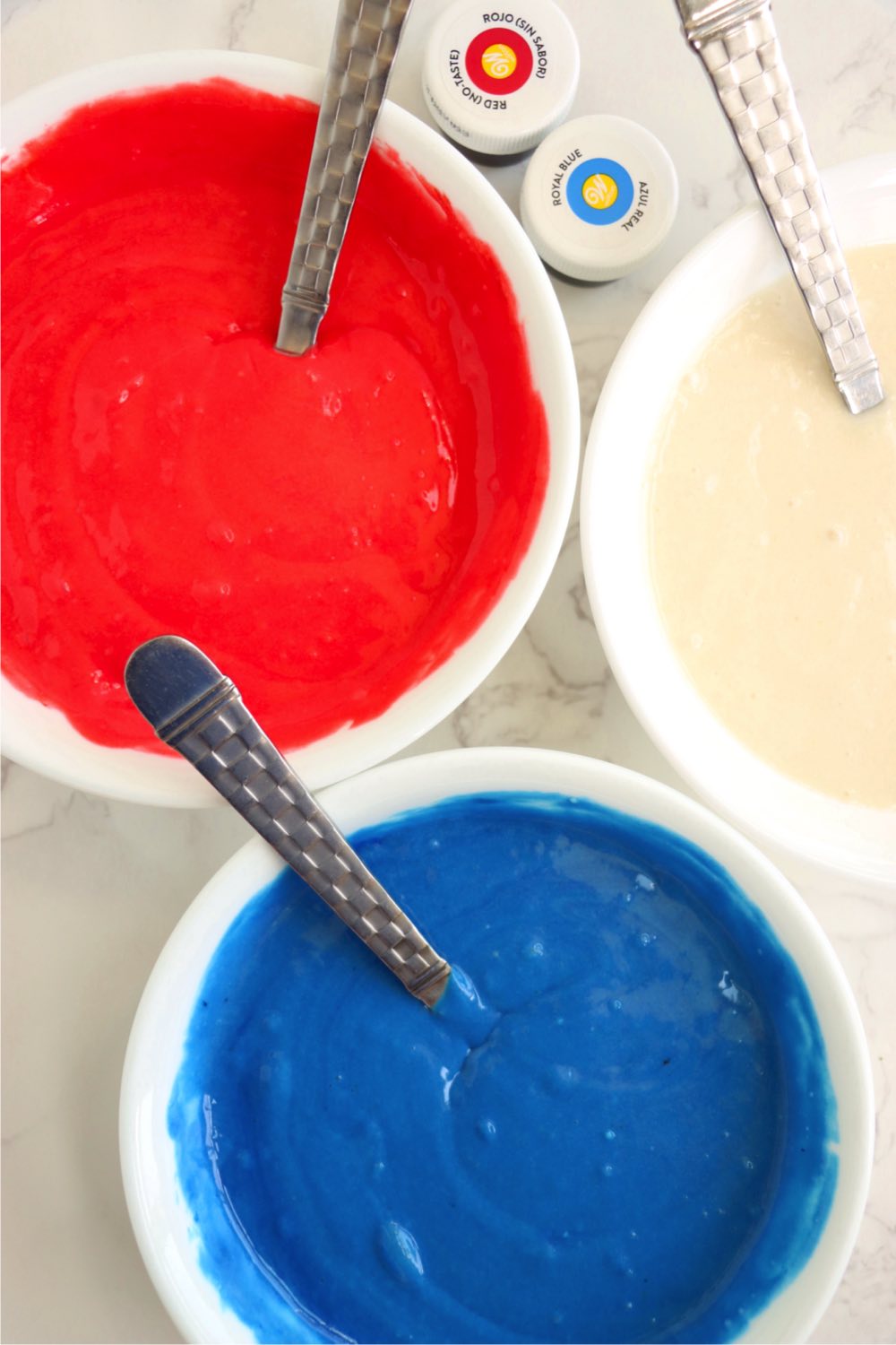 Three bowls filled with red, white and blue cake batter.
