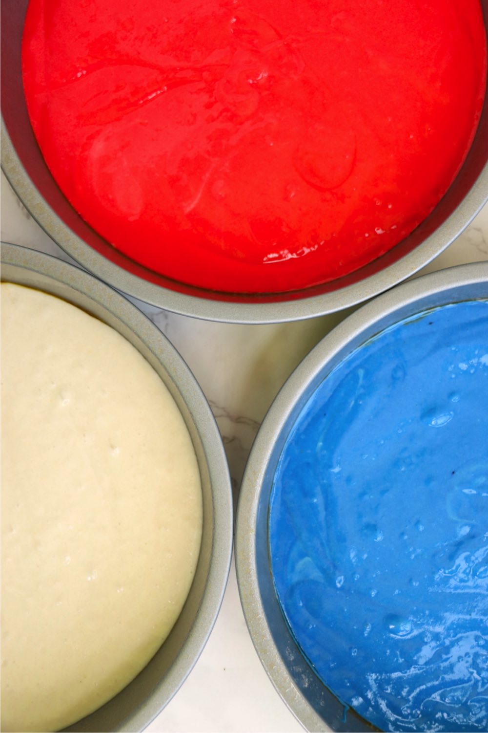 cake pans filled with red, white and blue raw cake batter.