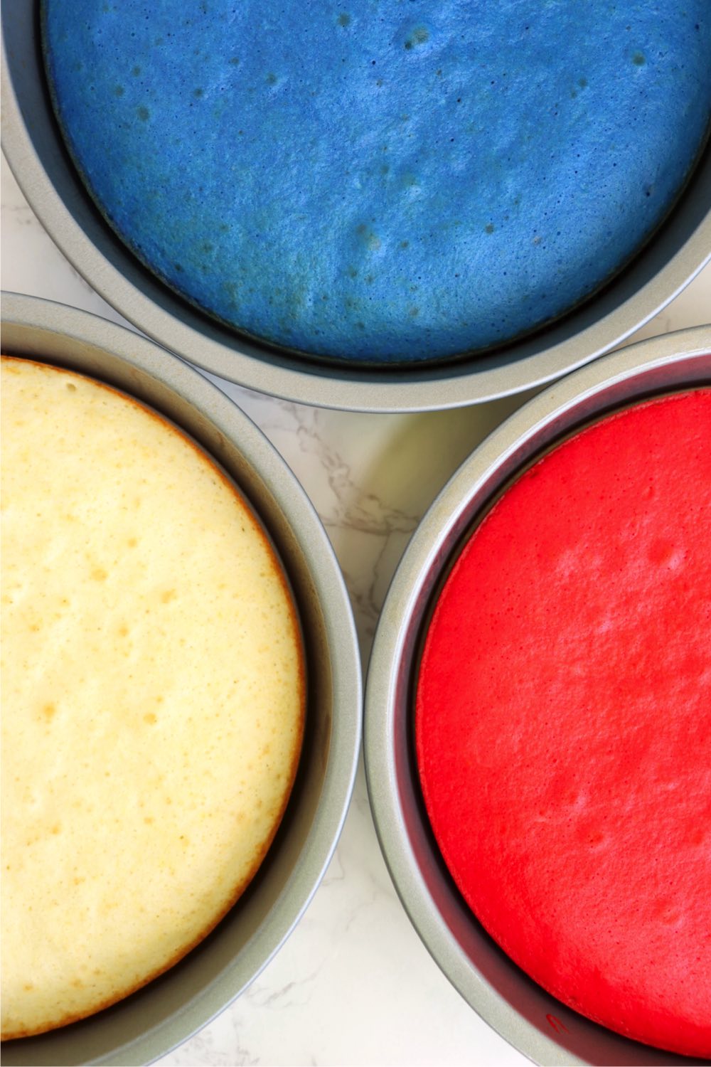 Three red, white and blue baked cakes in cake pans.