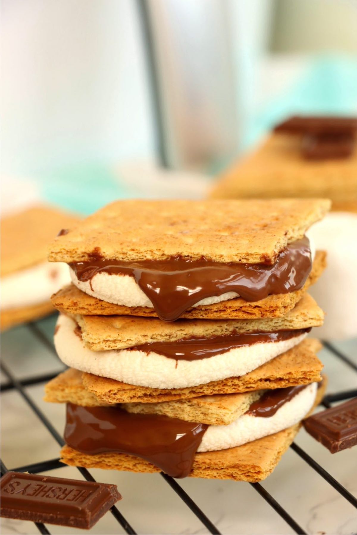 Stack of gooey s'mores with melted chocolate on a cooling rack.