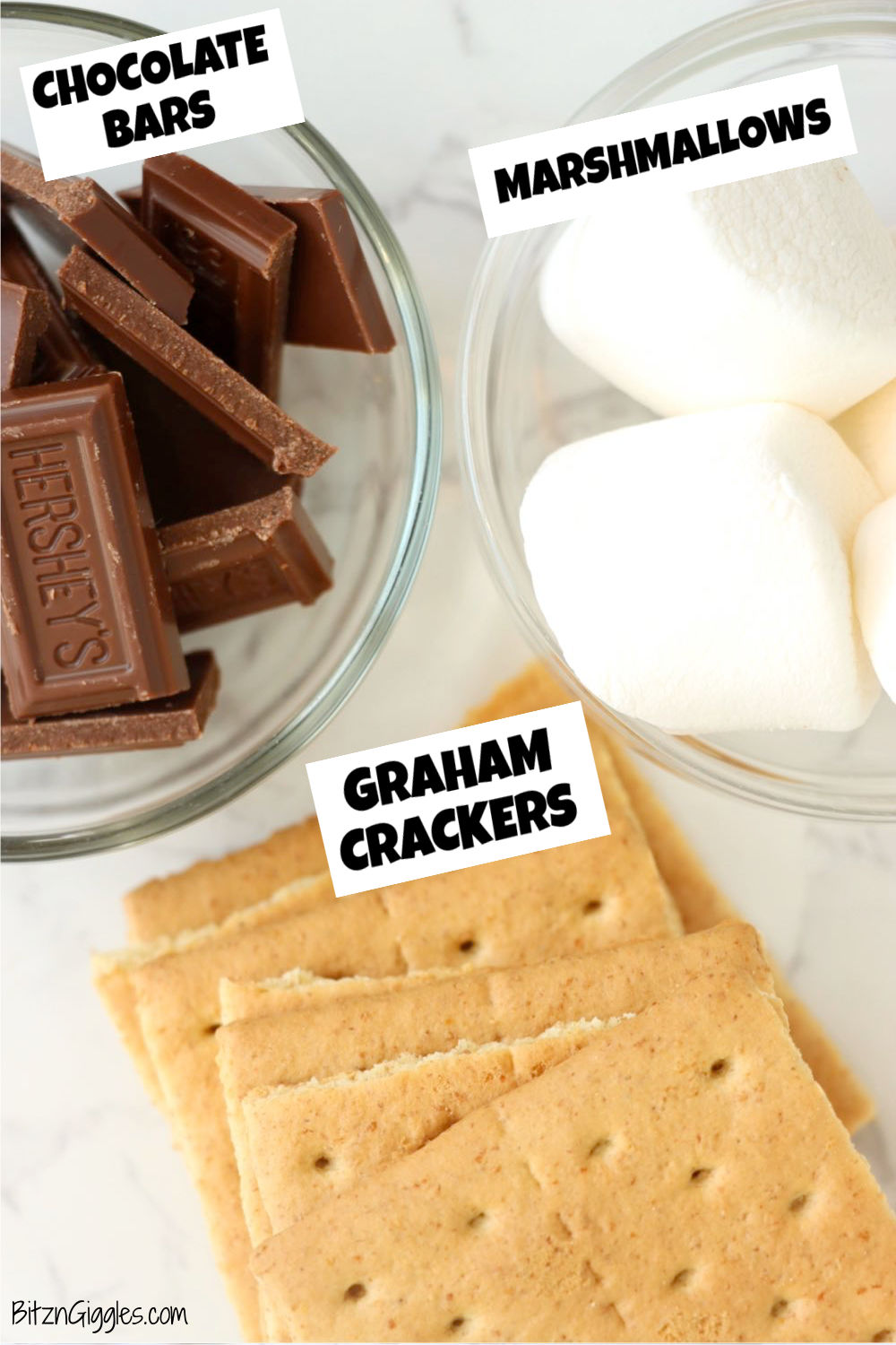 Chocolate bar pieces, marshmallows and graham crackers on a white table.