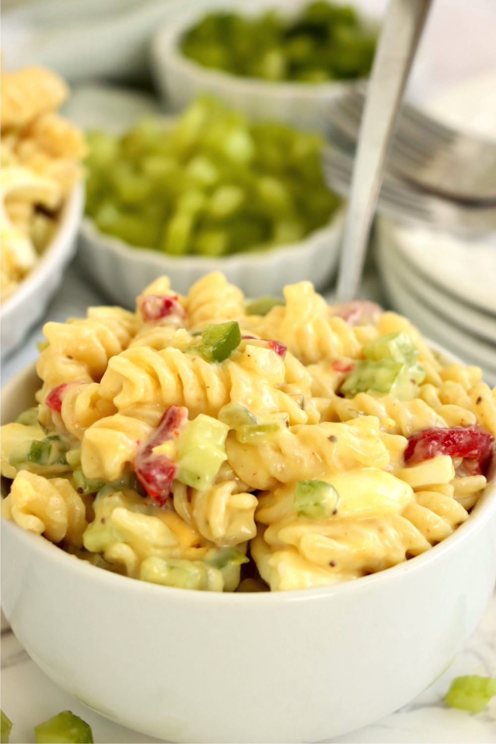 Small white bowl filled with a creamy pasta salad with spoon sticking out.