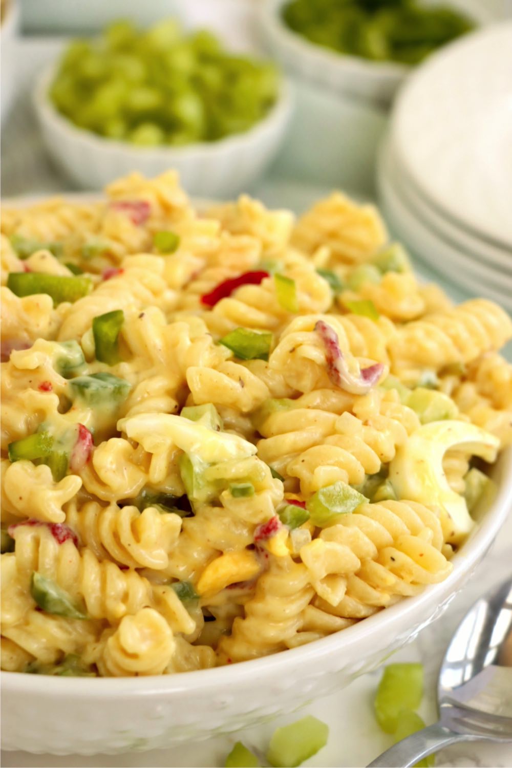 A white bowl filled with a creamy macaroni salad garnished with celery and pimentos.