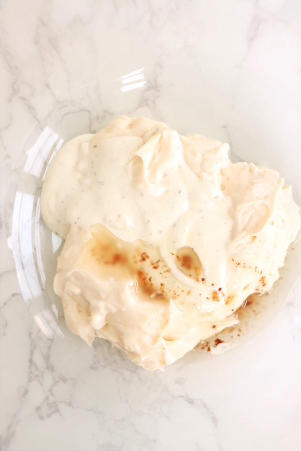 Glass mixing bowl filled with Miracle Whip, ranch dressing and bacon grease.