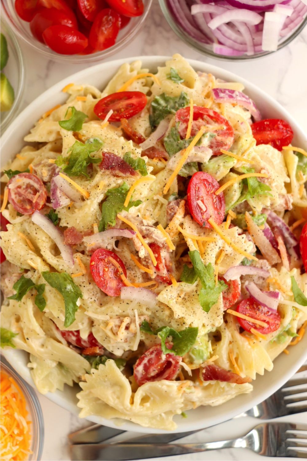 bowl filled with a creamy bowtie pasta salad garnished with tomatoes and lettuce.