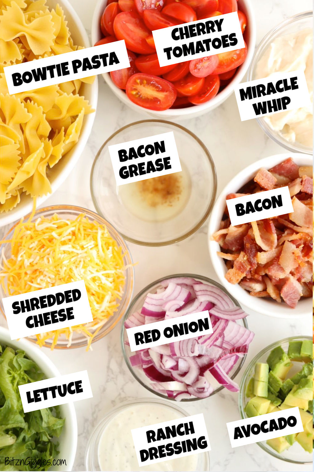 glass bowls filled with ingredients for a BLT pasta salad on a marble table.