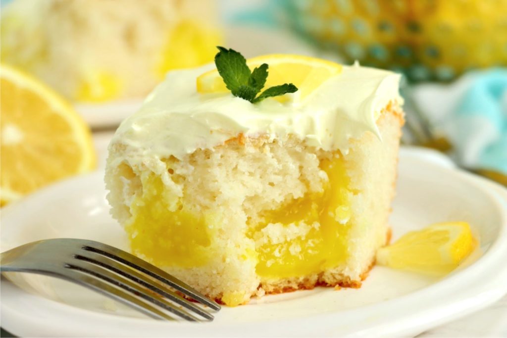Piece of lemon cake garnished with mint on a white plate.