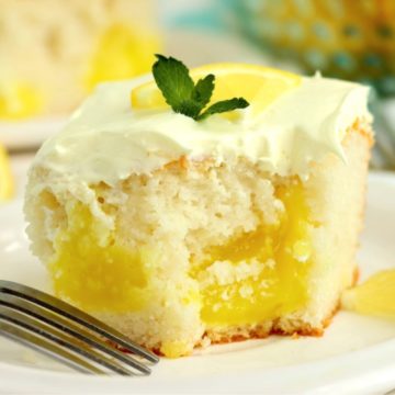 Piece of lemon cake garnished with mint on a white plate.