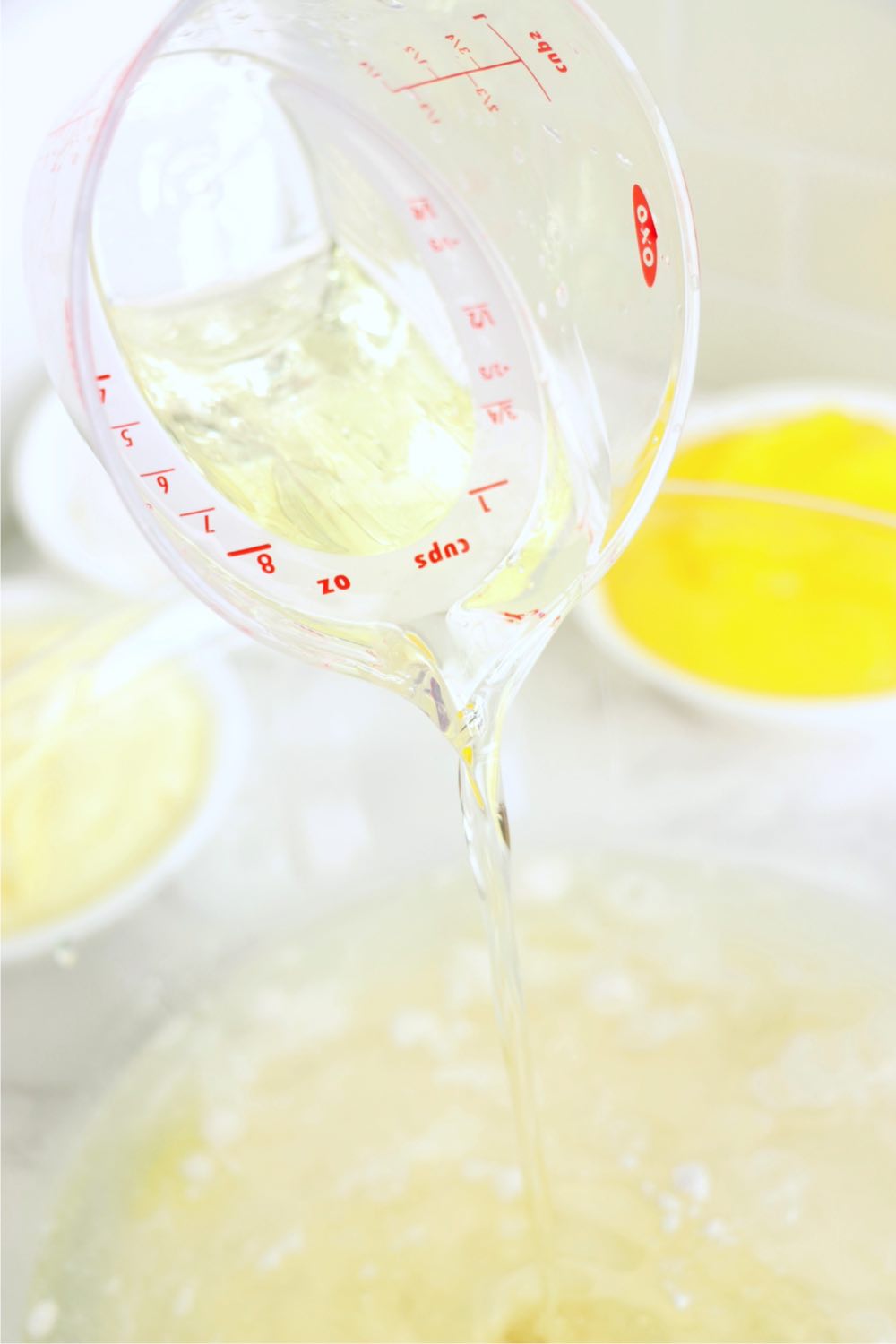 Pouring oil from a measuring cup into a bowl of cake batter.