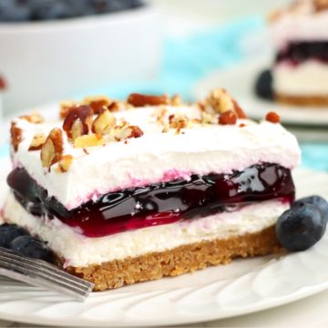 Piece of layered blueberry dessert on a white plate.