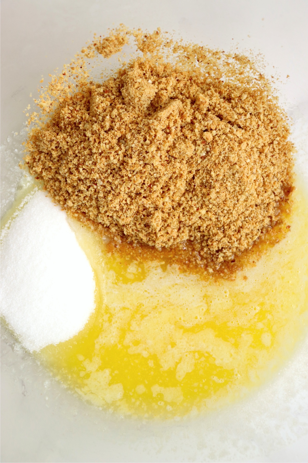 Butter, sugar and graham cracker crumbs in a bowl.