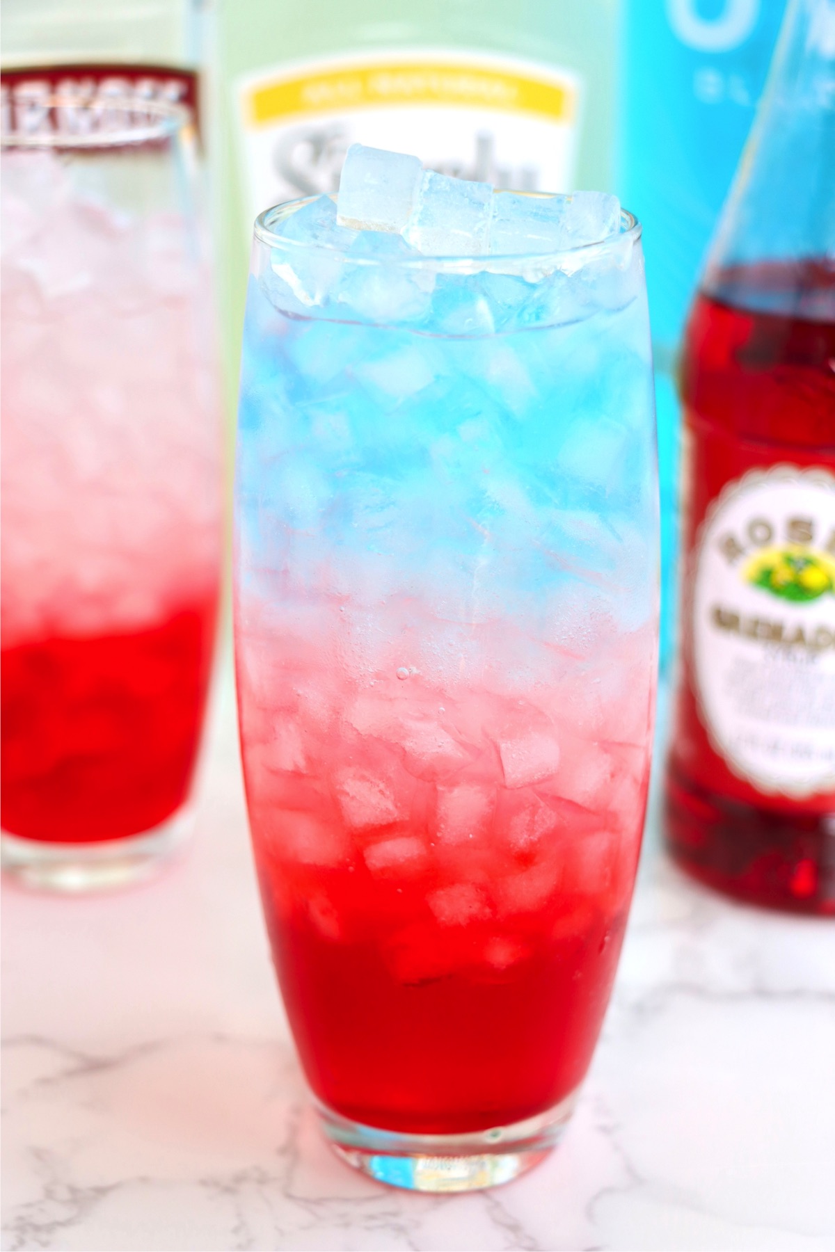 Tall ice-cube filled drink colored red, white and blue.