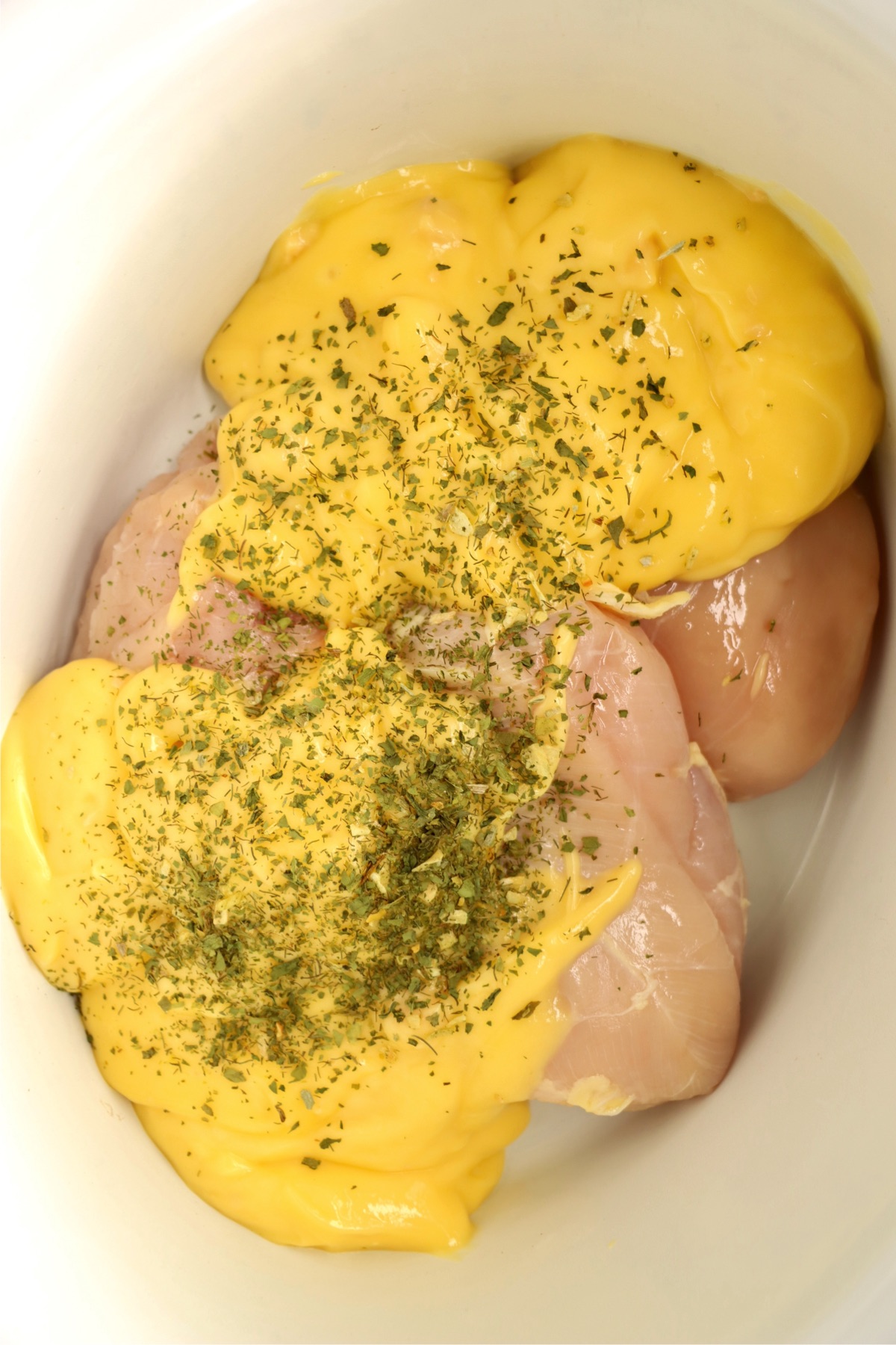 Chicken breasts in a crock pot covered with cream of chicken soup and seasonings.