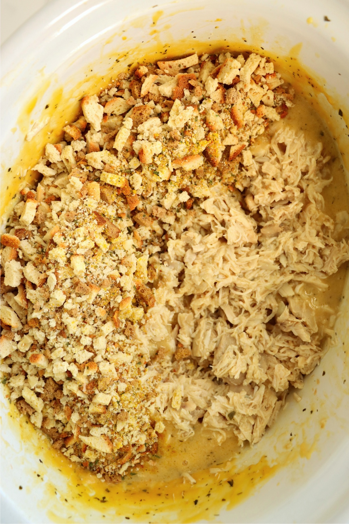 Stuffing mix on top of shredded chicken in a slow cooker.