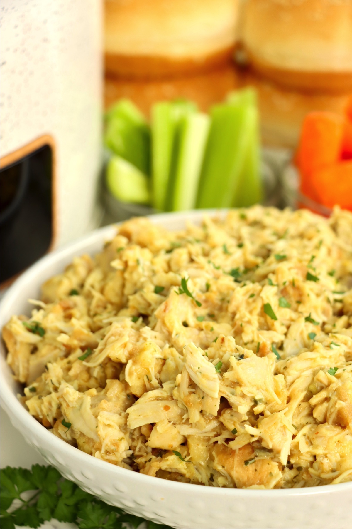 White serving bowl filled with creamy, shredded chicken.