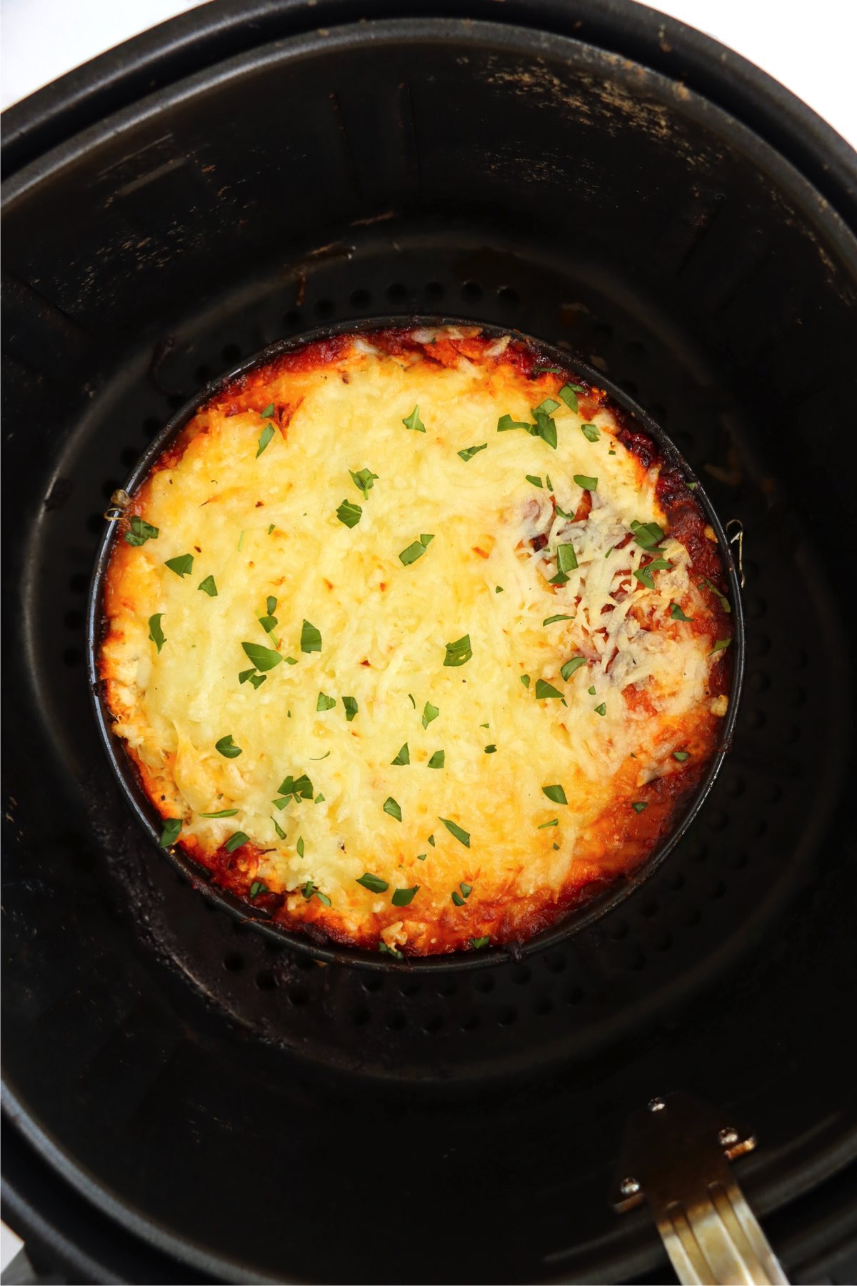 Small pan of lasagna in an air fryer basket.