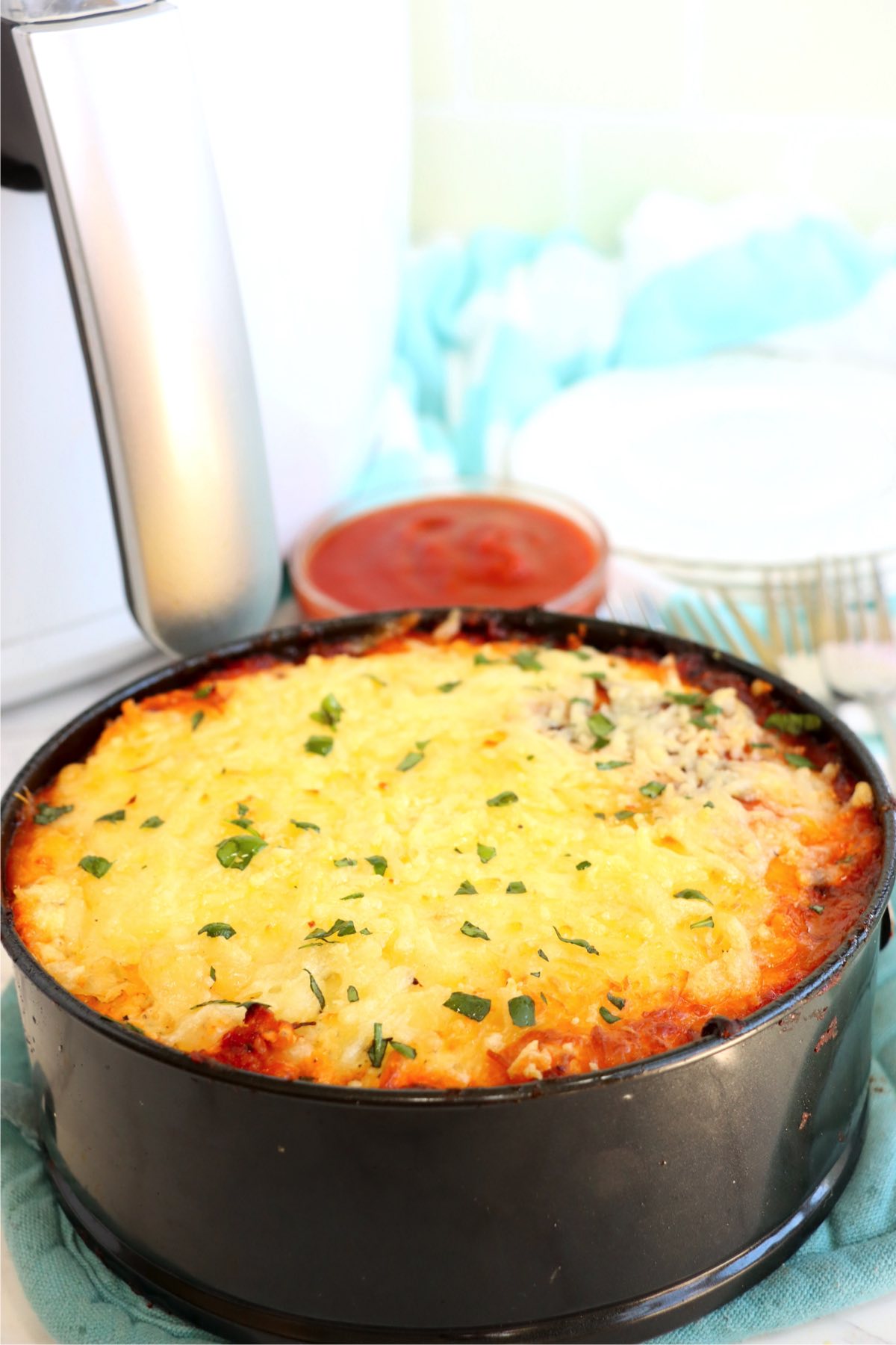 Air fryer lasagna in round black baking pan.