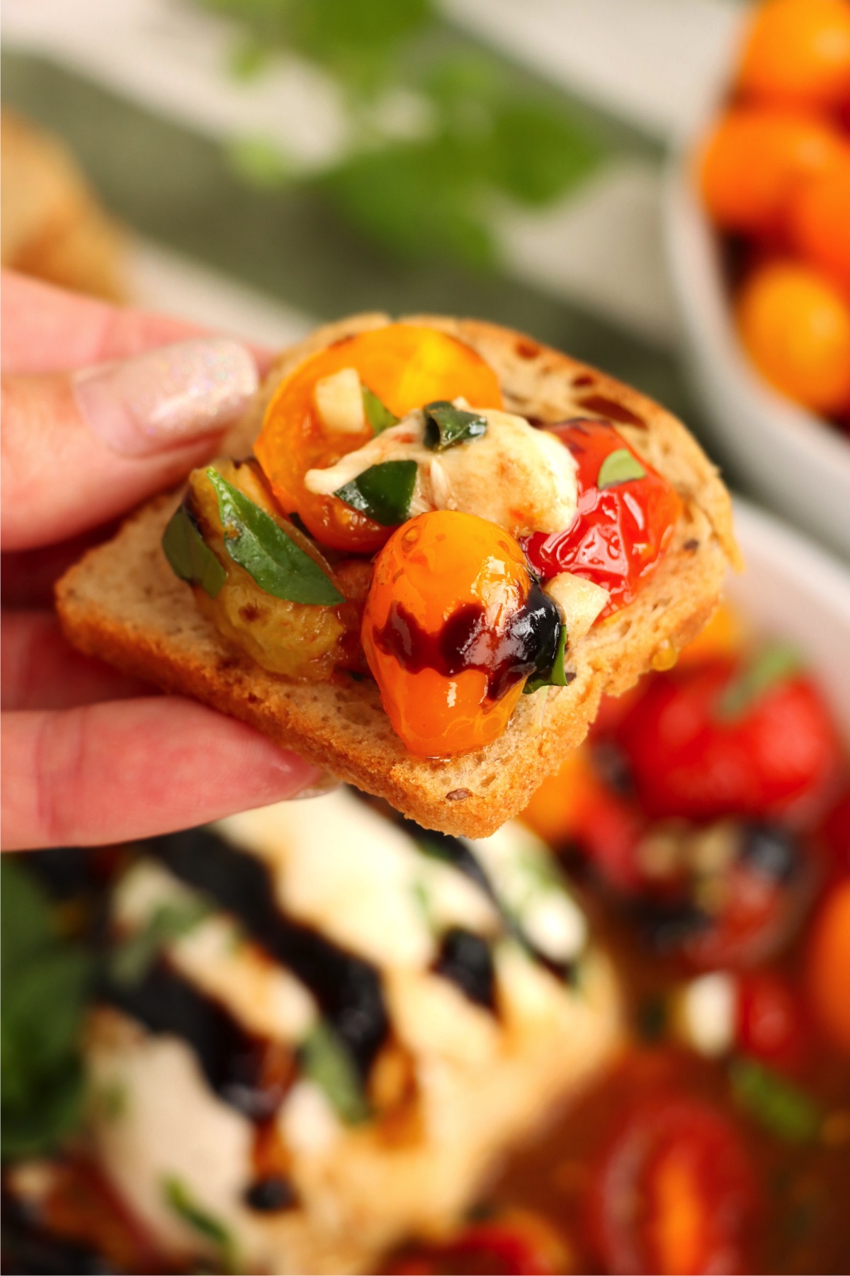 Hand holding a baguette slice covered with a tomato mixture.