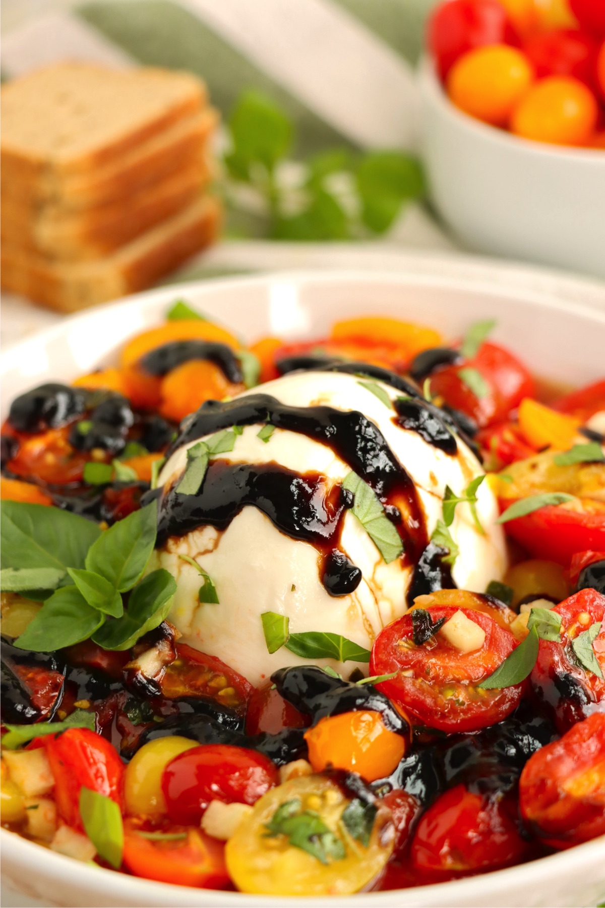 Ball of mozzarella in the middle of roasted cherry tomatoes.