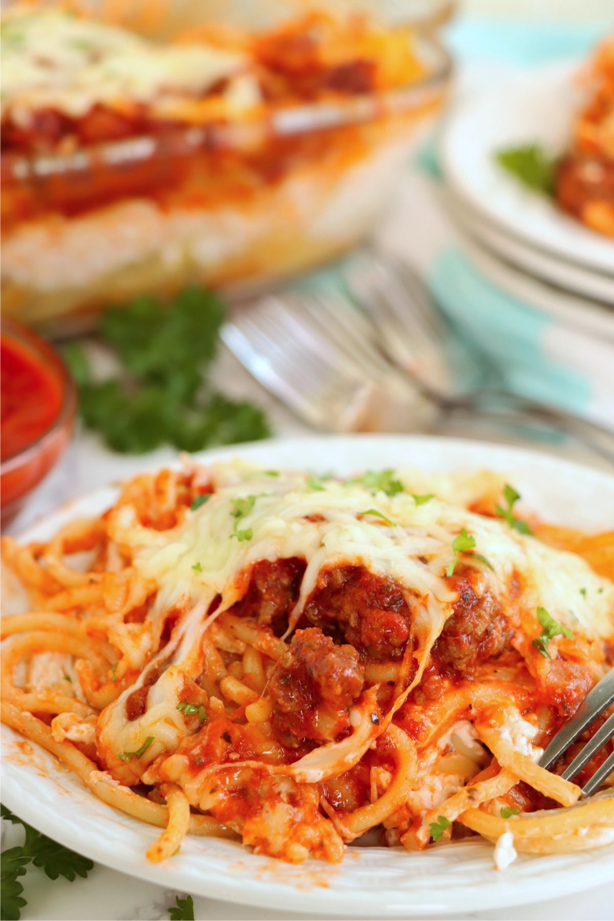 Serving of cheesy spaghetti on a small white plate.